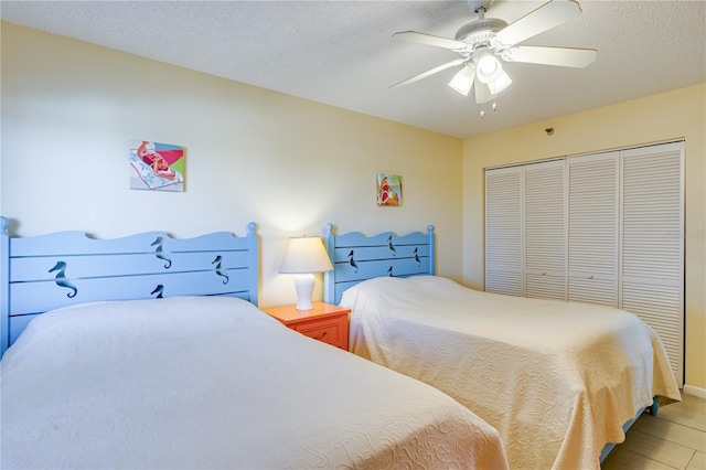 bedroom featuring ceiling fan, light tile patterned floors, a textured ceiling, and a closet