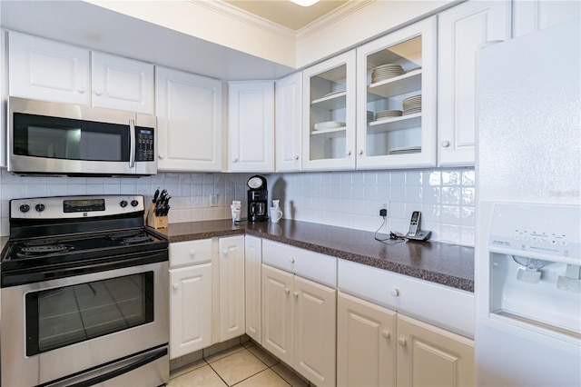 kitchen with white cabinets, decorative backsplash, ornamental molding, light tile patterned flooring, and stainless steel appliances