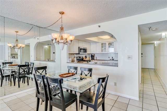 tiled dining area with a textured ceiling and a notable chandelier