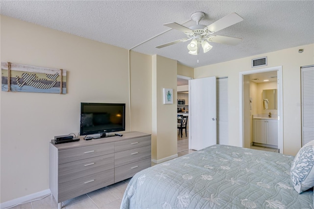 bedroom featuring light tile patterned floors, a textured ceiling, ceiling fan, and connected bathroom