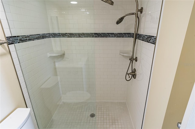 bathroom with toilet and a tile shower