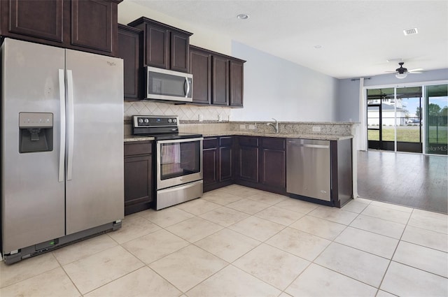 kitchen featuring light tile patterned flooring, decorative backsplash, ceiling fan, light stone counters, and stainless steel appliances