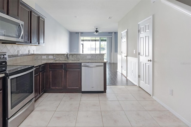 kitchen with sink, ceiling fan, light stone countertops, light tile patterned flooring, and stainless steel appliances