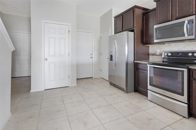 kitchen with light tile patterned floors, dark brown cabinets, stainless steel appliances, light stone countertops, and decorative backsplash