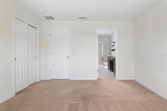 unfurnished bedroom with connected bathroom and light carpet