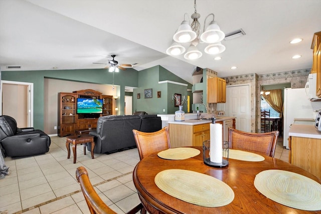 dining area with sink, ceiling fan with notable chandelier, vaulted ceiling, and light tile patterned flooring