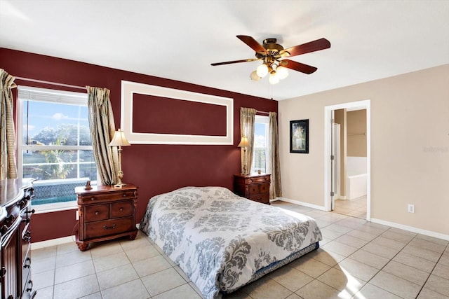 tiled bedroom featuring ensuite bath, multiple windows, and ceiling fan