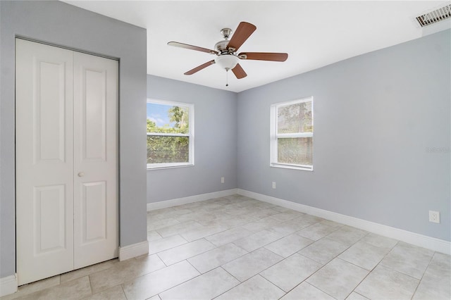 unfurnished bedroom with ceiling fan, light tile patterned flooring, and a closet