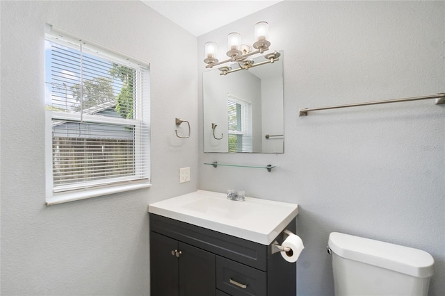 bathroom featuring plenty of natural light, toilet, and vanity