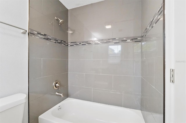 bathroom with toilet and tiled shower / bath