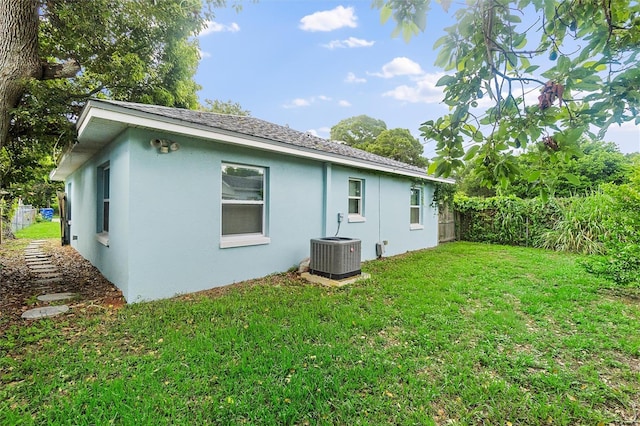 rear view of property with central air condition unit and a yard