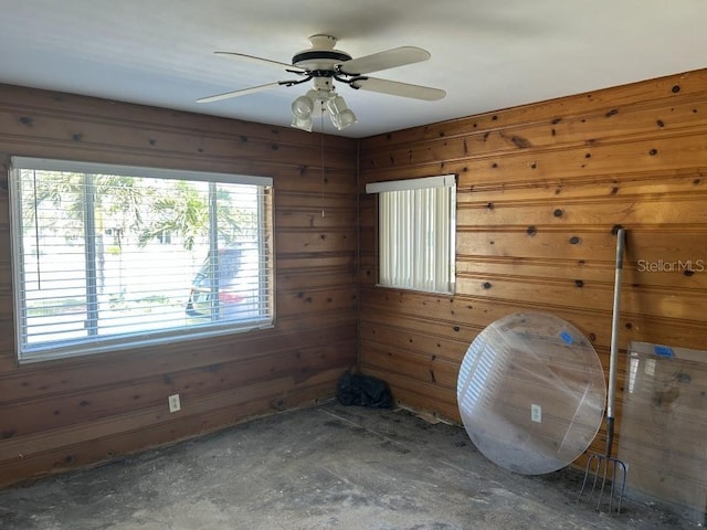 interior space with ceiling fan and wooden walls