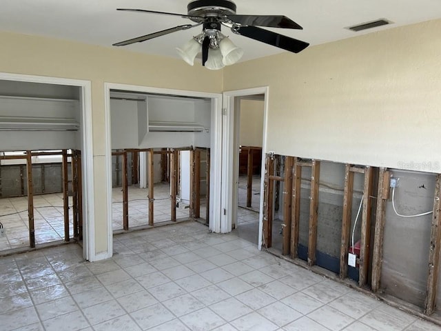 unfurnished bedroom with a ceiling fan, visible vents, and two closets