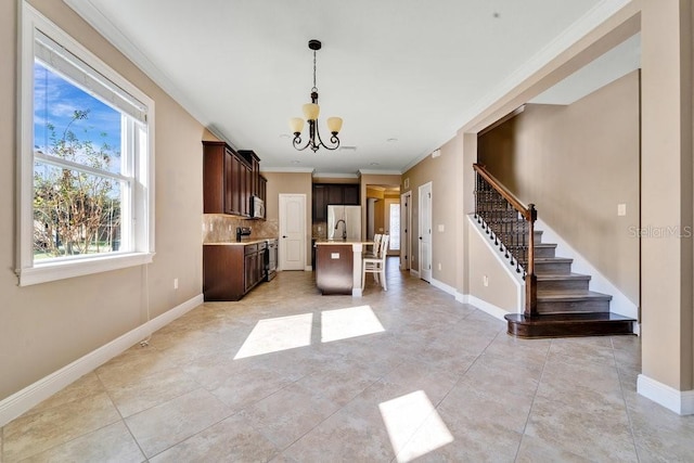 kitchen with a kitchen island with sink, decorative backsplash, ornamental molding, decorative light fixtures, and stainless steel appliances