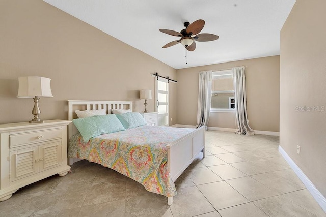 tiled bedroom featuring a barn door and ceiling fan