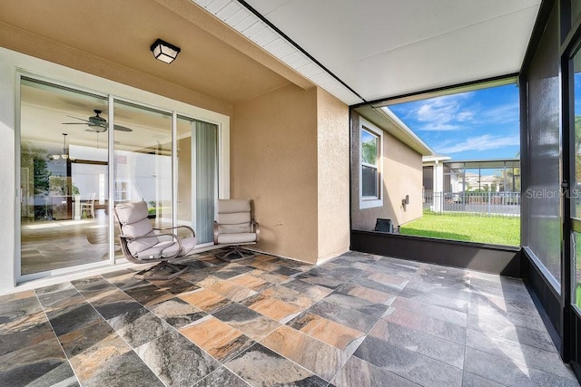 unfurnished sunroom with ceiling fan