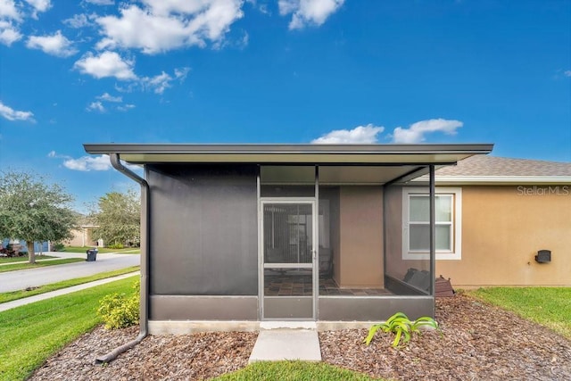 back of property with a sunroom and a yard