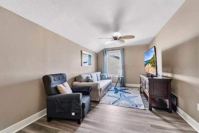 living room with a textured ceiling, hardwood / wood-style flooring, ceiling fan, and lofted ceiling