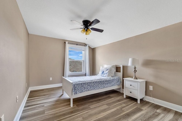 bedroom featuring hardwood / wood-style floors, ceiling fan, lofted ceiling, and a textured ceiling