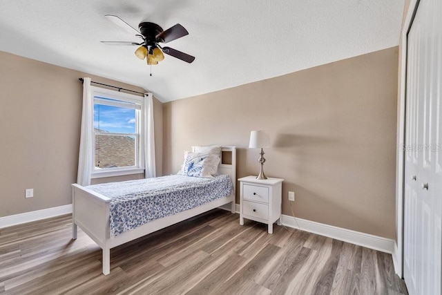 bedroom with a textured ceiling, ceiling fan, hardwood / wood-style flooring, a closet, and lofted ceiling