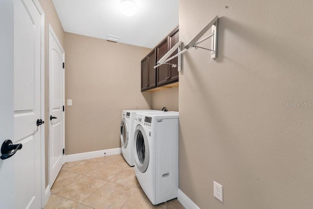 laundry area featuring cabinets, light tile patterned floors, and washing machine and dryer