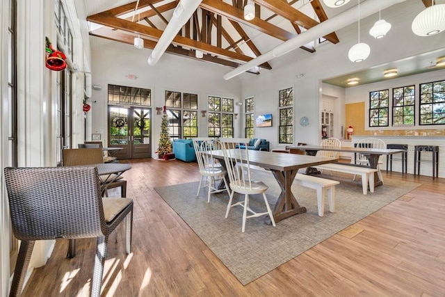 dining area with beamed ceiling, high vaulted ceiling, hardwood / wood-style floors, and french doors