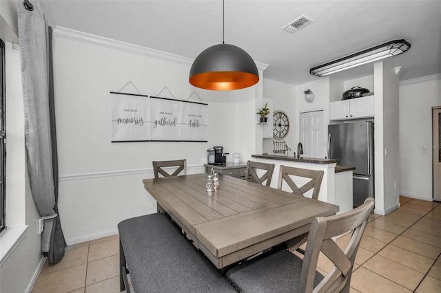 tiled dining room featuring ornamental molding and sink