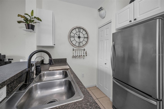 kitchen with white cabinetry, stainless steel fridge, sink, and light tile patterned floors