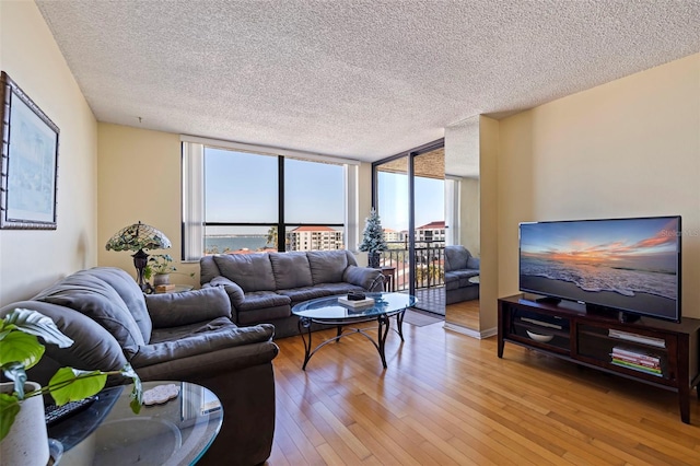 living room featuring light hardwood / wood-style flooring, expansive windows, and a textured ceiling