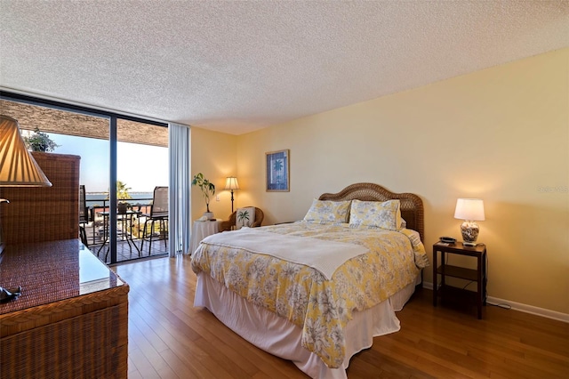 bedroom featuring a textured ceiling, access to outside, floor to ceiling windows, and hardwood / wood-style flooring