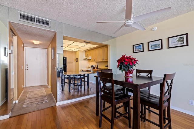 dining room featuring hardwood / wood-style floors, ceiling fan, and a textured ceiling