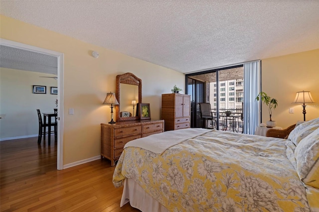 bedroom with hardwood / wood-style flooring, expansive windows, access to exterior, and a textured ceiling