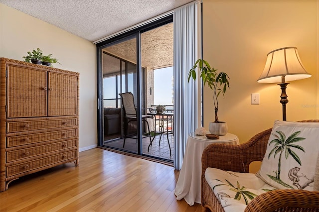 sitting room featuring a textured ceiling, light hardwood / wood-style flooring, and a wall of windows