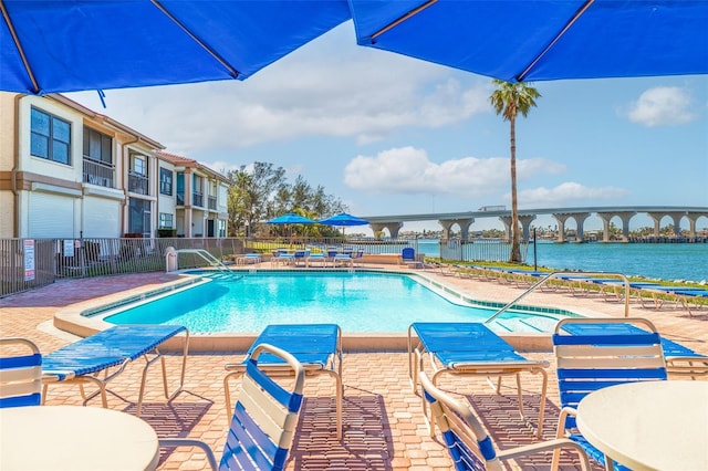 view of swimming pool with a patio area and a water view