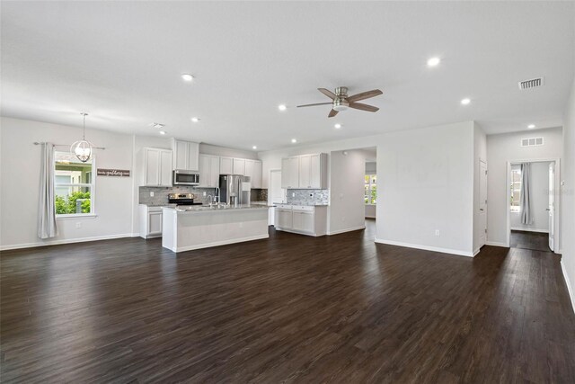 unfurnished living room with dark hardwood / wood-style flooring and ceiling fan