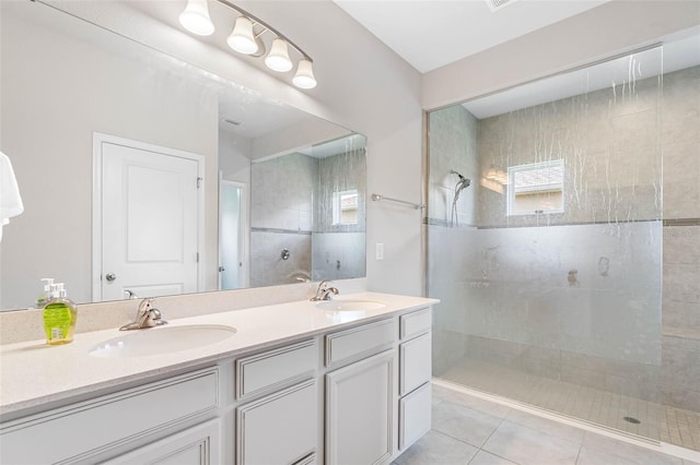 bathroom featuring tile patterned flooring, vanity, and tiled shower