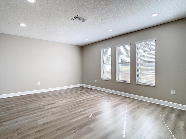 unfurnished room with a textured ceiling and light hardwood / wood-style flooring