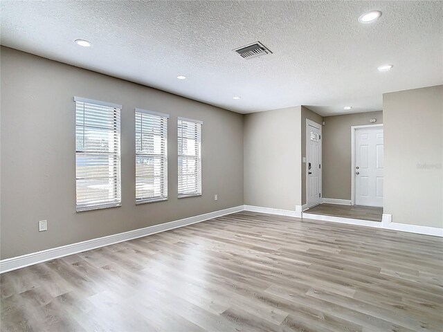 spare room featuring a textured ceiling and light wood-type flooring