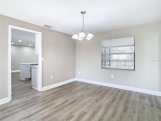 unfurnished room with light hardwood / wood-style floors and a notable chandelier