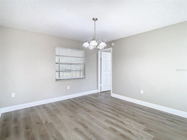 spare room with hardwood / wood-style floors, a chandelier, and a textured ceiling