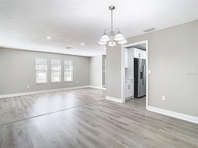 interior space with a notable chandelier, light hardwood / wood-style floors, and a textured ceiling