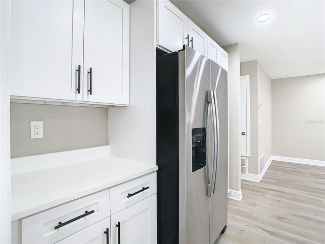 kitchen featuring white cabinets, light wood-type flooring, and stainless steel refrigerator with ice dispenser