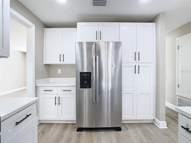 kitchen with white cabinets, light wood-type flooring, and stainless steel fridge with ice dispenser