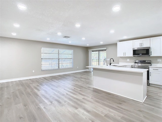 kitchen with sink, white cabinets, light hardwood / wood-style floors, and appliances with stainless steel finishes