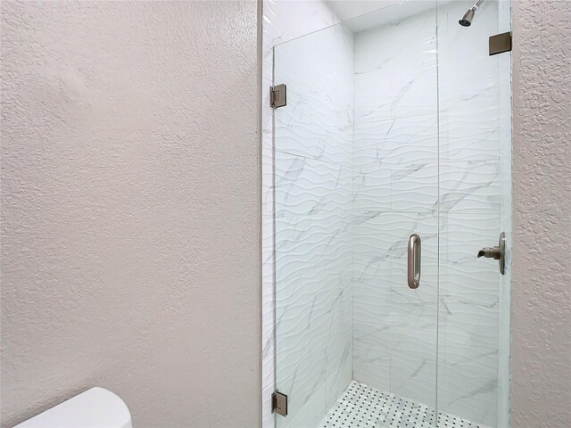 bathroom with toilet and a shower with shower door