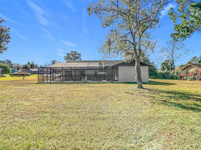 rear view of house featuring glass enclosure and a lawn