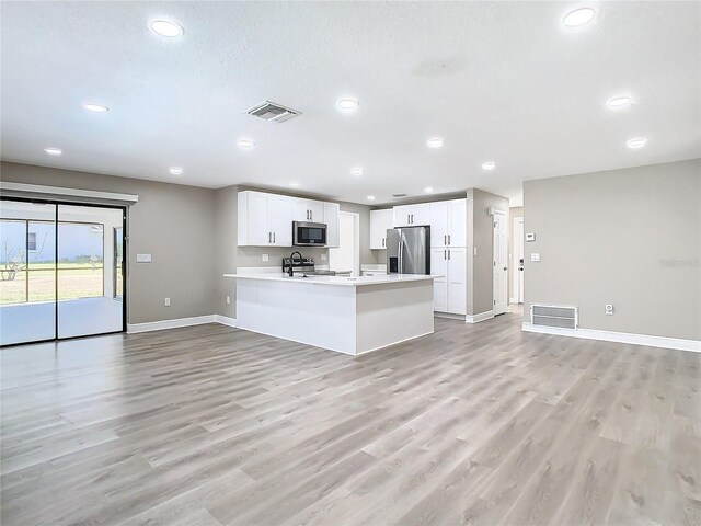 kitchen with kitchen peninsula, white cabinets, stainless steel appliances, and light wood-type flooring