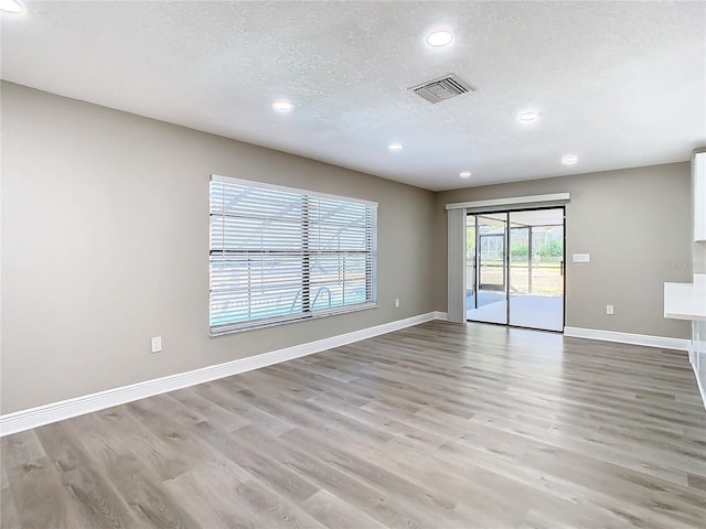 unfurnished room featuring light hardwood / wood-style floors and a textured ceiling