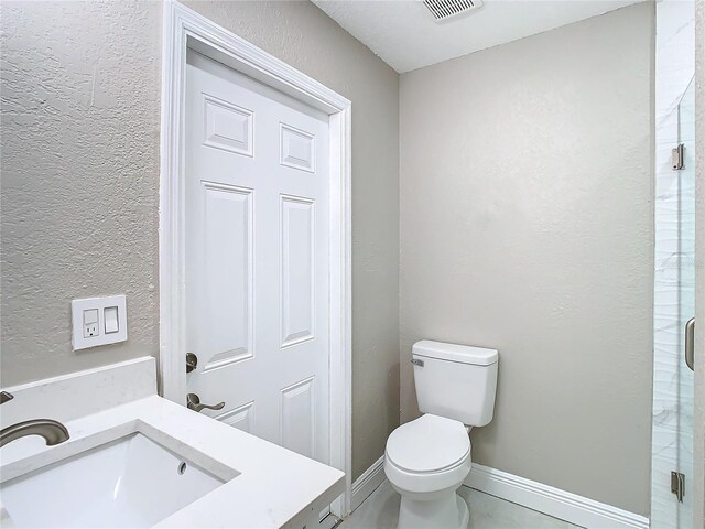 bathroom featuring sink, an enclosed shower, and toilet