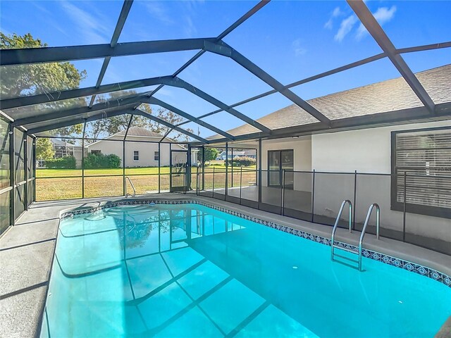 view of pool with a lawn, glass enclosure, and a patio area